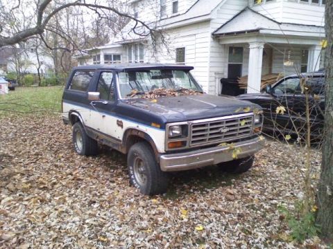 1986 Ford Bronco - This 1986 Ford Bronco XLT is parked on a leaf-covered lawn next to a house.