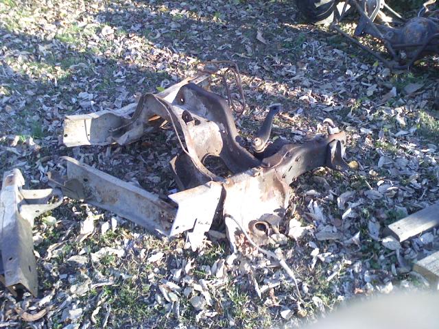 rusted metal frame pieces lying on the ground covered in leaves