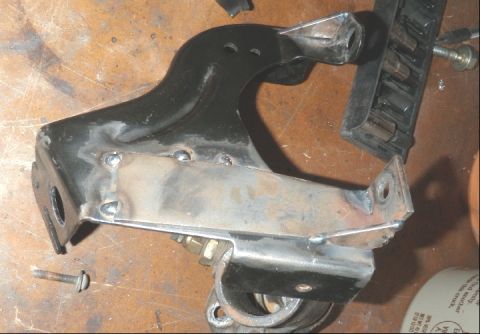 1994 Ford Bronco - A modified suspension part, likely for a vehicle swap, is shown on a workbench with tools and hardware.
