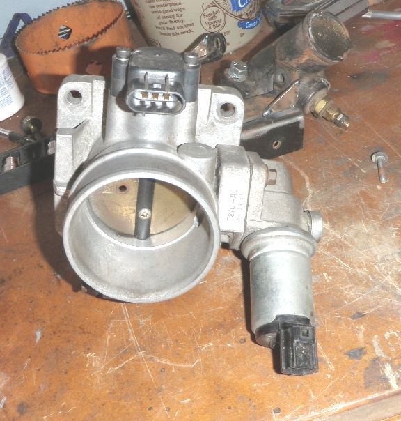 Throttle body assembly with electrical connector and idle air control valve on a wooden surface