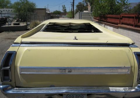 1972 Ford Ranchero - Rear view of a light yellow Ford Ranchero showing the tailgate with 'FORD' lettering in chrome trim, vertical taillights, and rear window l…