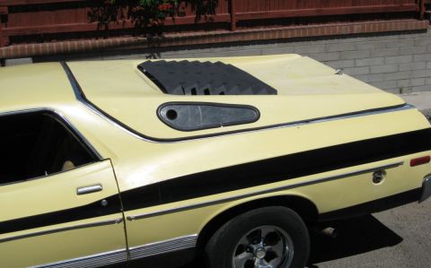 1972 Ford Ranchero - Rear three-quarter view of a pale yellow Ford Ranchero-style car-truck with a black hood scoop featuring louvers and a teardrop-shaped acce…