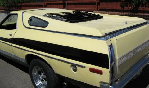 1972 Ford Ranchero - Rear-quarter view of a pale yellow mid-1970s Ford Ranchero with a black bodyside stripe, chrome trim and an open sunroof.