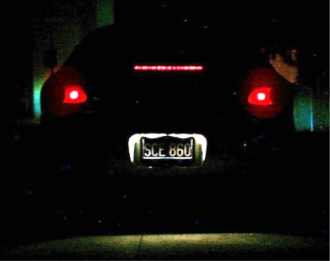 1990 Ford Taurus - Car's rear end with illuminated taillights and license plate at night.