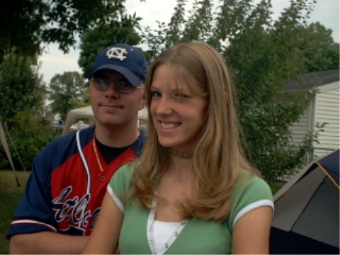 1990 Ford Taurus - A couple poses for a photo outdoors, with trees and a house in the background.
