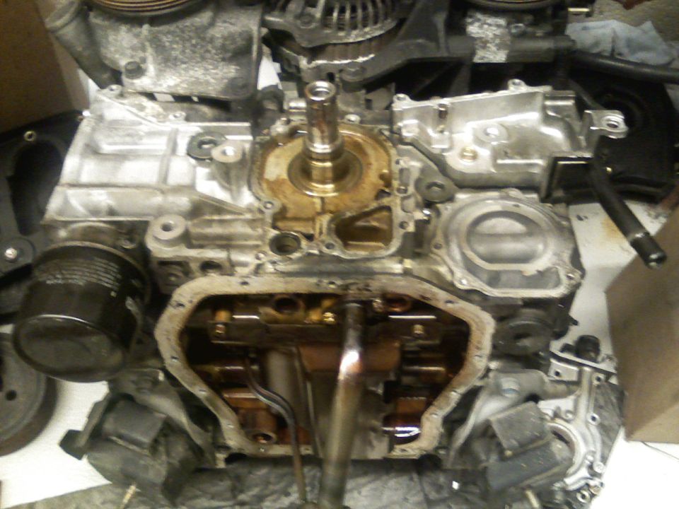 Engine block with oil pan removed, showing crankshaft and connecting rods. Oil filter visible on the left