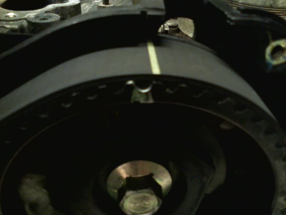 Close-up of a black timing belt with a yellow mark and a metal pulley with a bolt