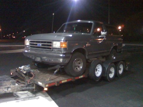 1988 Ford Bronco - A gray 1988 Ford Bronco is seen being transported on a trailer at night.