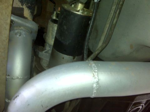 1994 Ford F-150 - Close-up view of a starter motor and exhaust pipe, likely from a truck.