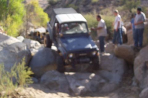 1981 Ford F-150 - A group of people watch as a blue Suzuki Samurai navigates a rocky trail.