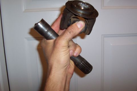 1981 Ford F-150 - A driveshaft U-joint and yoke assembly is held up for inspection.