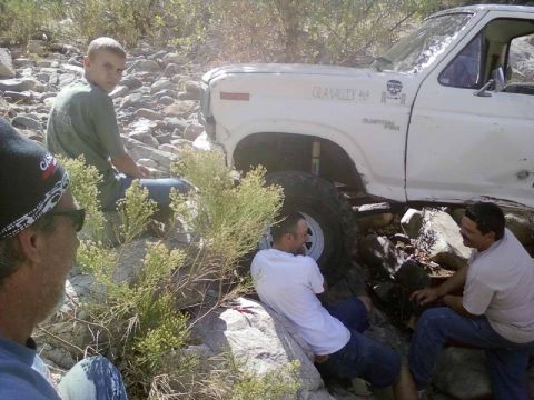 1981 Ford F-150 - A group of people gather around a white 1981 Ford F-150 that appears to be stuck on a rocky trail.