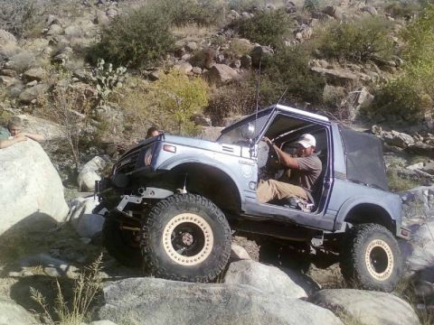 1981 Ford F-150 - Suzuki Samurai tackling a challenging rocky trail with a driver at the wheel.