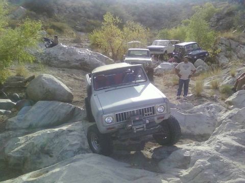 1981 Ford F-150 - Several off-road vehicles are navigating a rocky trail in a mountainous area.