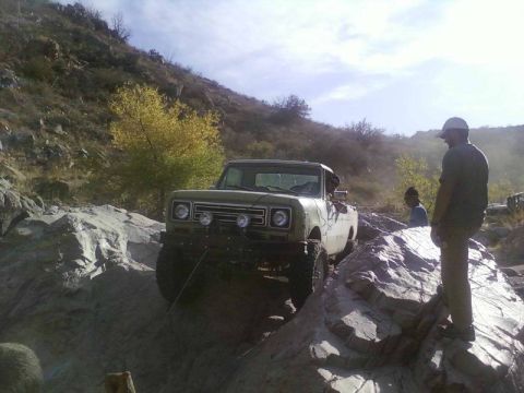 1981 Ford F-150 - An off-road vehicle navigates a challenging rocky terrain under a partly cloudy sky.