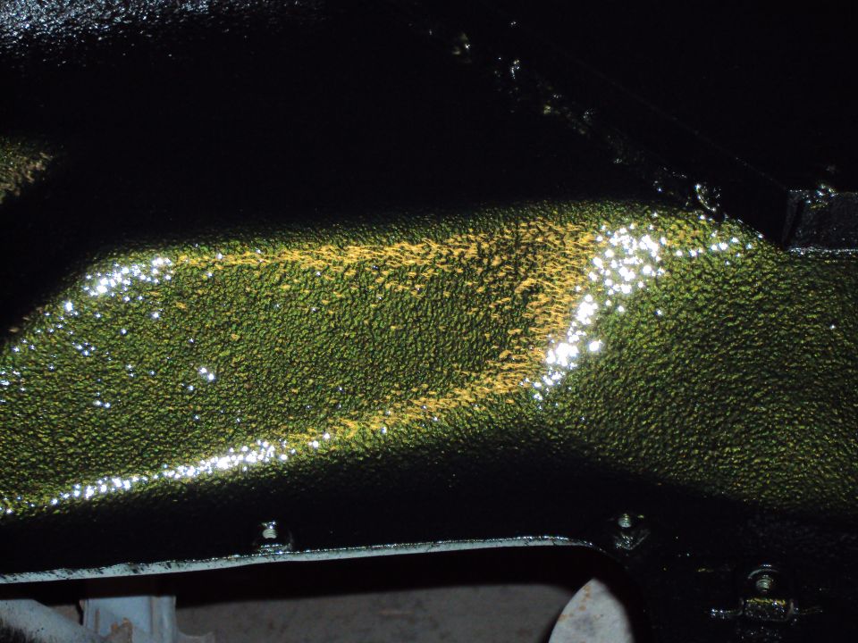 Underside of vehicle frame with textured green and yellow paint