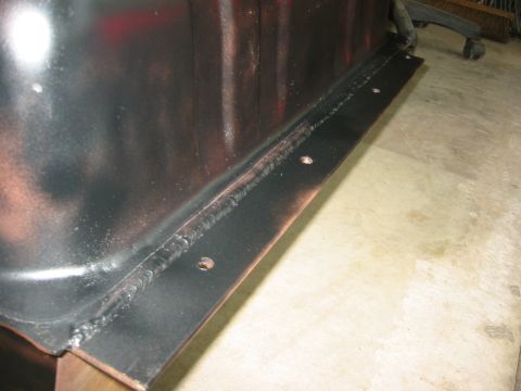 1995 Ford Bronco - A close-up view of a welded metal bracket with visible bolt holes, attached to a dark surface.