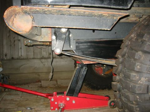 1995 Ford Bronco - A 1995 Ford Bronco's rear suspension and tire are visible, supported by a red floor jack.