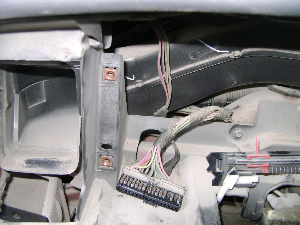 Close-up of a car's dashboard wiring harness with multiple colored wires and connectors