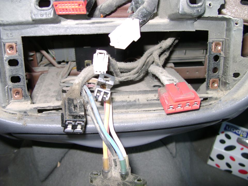 Car dashboard wiring connectors and cables. Some red and white connectors are visible