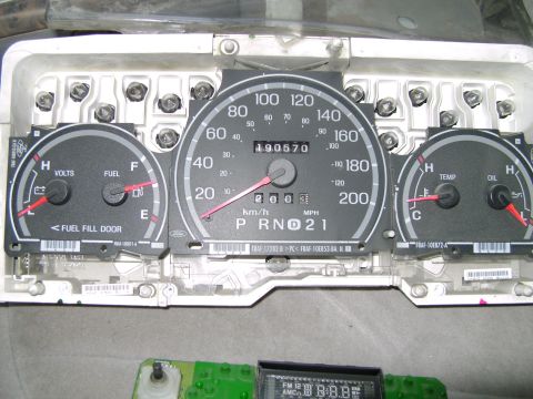 1998 Ford Crown Victoria - Photo of a removed Ford F-series instrument cluster reading 190,570 km/h-and-mph dual scale, PRND21 column shift, with cluster part numbers…