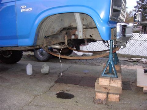 1980 Ford Bronco - The rear suspension of a blue Ford Bronco is visible while it's raised on jack stands for maintenance.