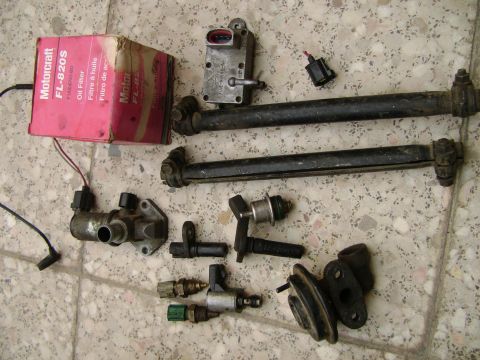 1998 Ford Crown Victoria - Assortment of automotive parts, including an oil filter and sensors, laid out on a tiled floor.