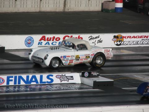 1968 Ford Mustang - A classic Chevrolet Corvette dragster races down the strip, adorned with numerous sponsor decals.