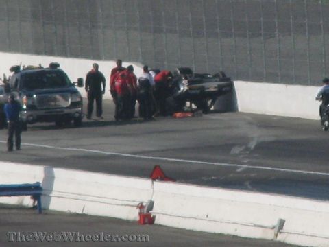 1968 Ford Mustang - Safety crew attends to an overturned race car on the track, with a support truck and motorcycle present.