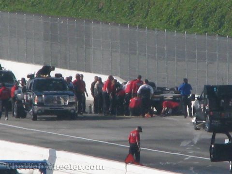 1968 Ford Mustang - Emergency personnel attend to a vehicle on a race track, with a support truck present.