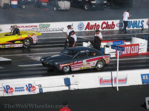 1968 Ford Mustang - A vintage coupe drag car with numerous sponsor decals races down the track at an NHRA event.