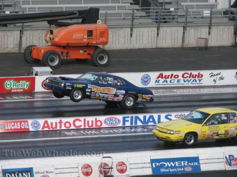 1968 Ford Mustang - Two drag racing cars compete on a track, with an orange lift in the background.