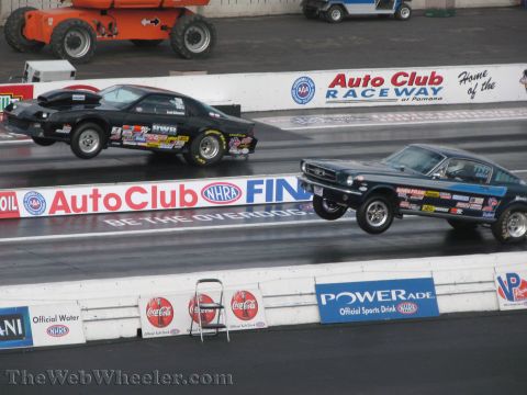 1968 Ford Mustang - Two drag cars, a 1967 Ford Mustang and a Camaro, launch off the starting line at a race.