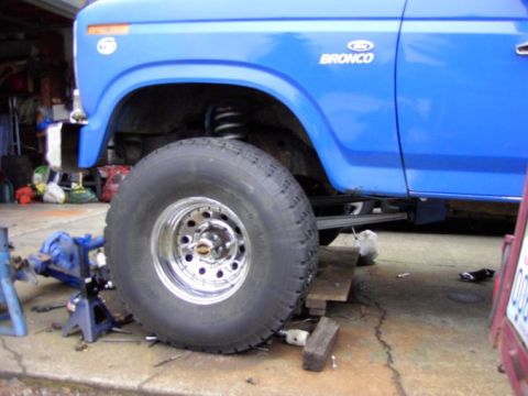 1980 Ford Bronco - Blue 1980 Ford Bronco undergoing work, with large tires and suspension visible.