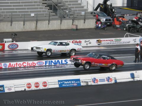 1968 Ford Mustang - Two drag cars compete on a track during an NHRA event, with multiple sponsors visible on the barriers.