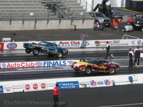 1968 Ford Mustang - A blue 1969 drag car launches with its front wheels in the air during a race at Auto Club Raceway.