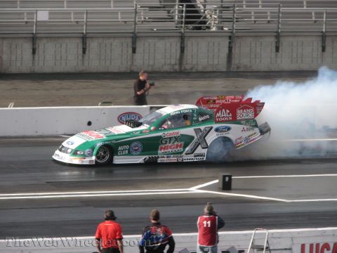 1968 Ford Mustang - Funny Car dragster performing a burnout at a drag racing event. John Force is the driver.