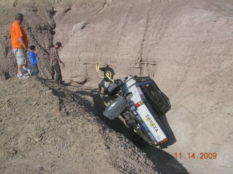 1985 Ford Bronco - A Toyota SUV is stuck on its side in a ditch, with onlookers gathered nearby. The date 11.14.2009 is visible.