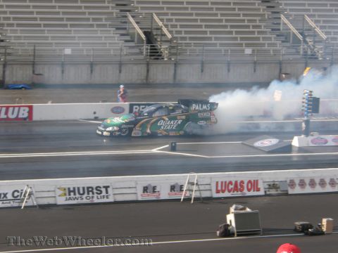 1968 Ford Mustang - A drag racing car with Quaker State livery performs a burnout on a track, generating smoke.