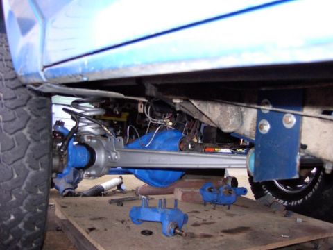 1980 Ford Bronco - Undercarriage view shows suspension components removed for service, with blue-painted parts laid out.