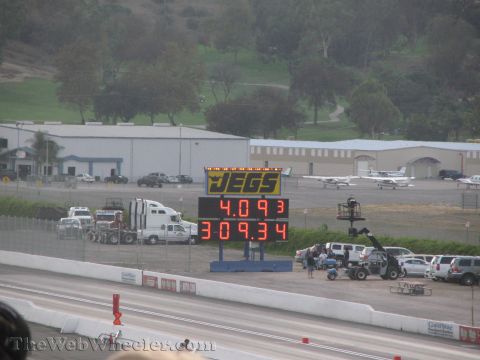 1968 Ford Mustang - A drag strip scene with a JEGS scoreboard showing race times, surrounded by various vehicles and buildings.