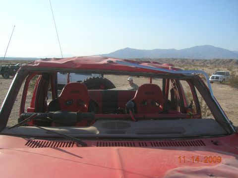 1985 Ford Bronco - A modified buggy with racing seats sits in a desert landscape with other vehicles nearby.