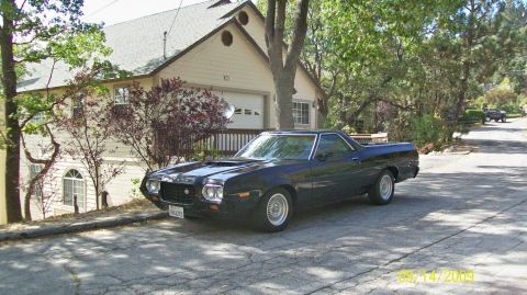 1972 Ford Ranchero - This dark blue 1972 Ford Ranchero, identifiable by its distinctive body style and hood scoop, is parked on a tree-lined street in front of…