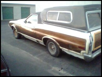 1972 Ford Ranchero - This 1972 Ford Ranchero features a distinctive wood-paneled body and a camper shell, seen from the front three-quarter angle.