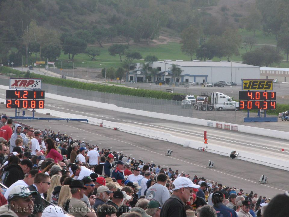 Crowd watching drag race with scoreboards showing times