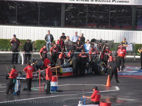 1968 Ford Mustang - A drag racing team prepares their vehicle on the track, with spectators in the background.