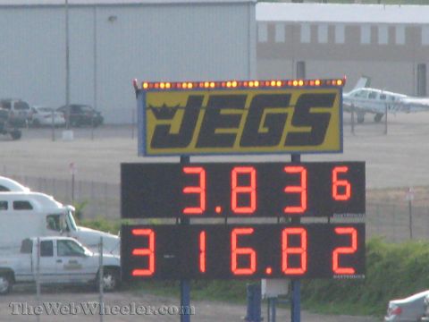 1968 Ford Mustang - Digital scoreboard displays race times at a drag strip, with vehicles and a plane visible.