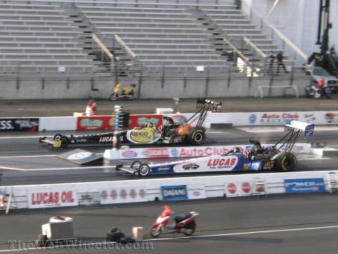 1968 Ford Mustang - Two dragsters race down the track during the 2009 NHRA Finals Qualifying, with one car experiencing engine flare.