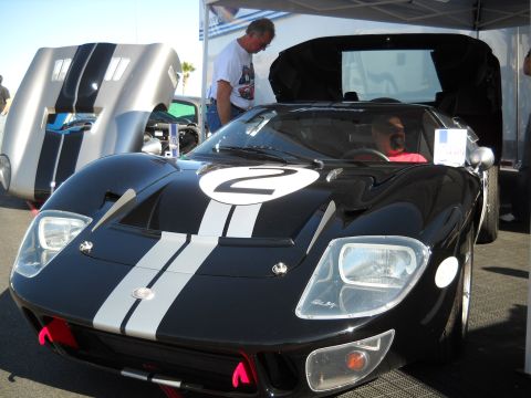 1986 Ford Bronco II - A black Ford GT40 with racing stripes is parked next to another silver car with its hood open.