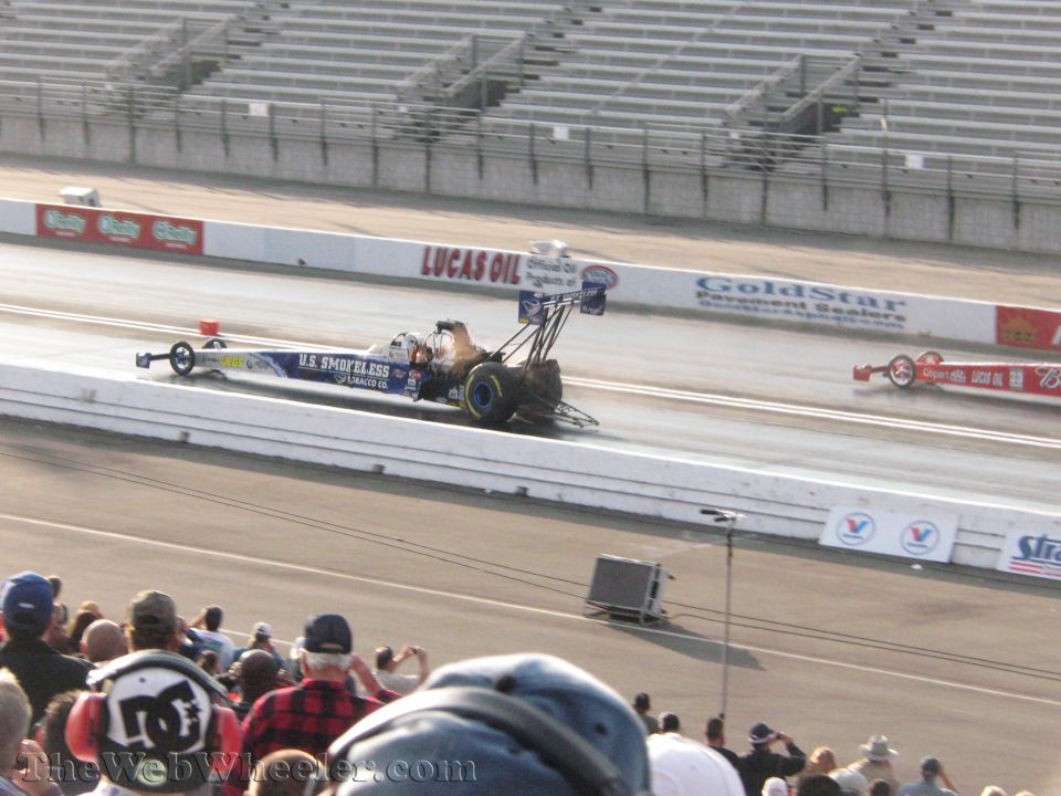 Drag racing cars on track with spectators in foreground